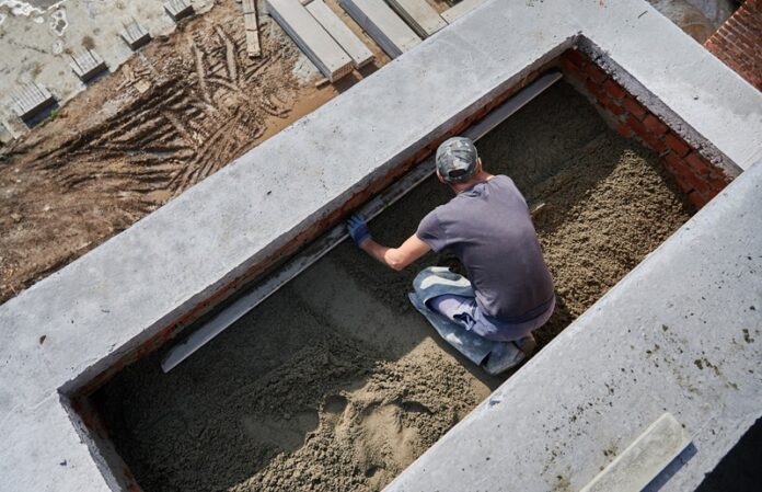 Male worker screeding floor at construction site. Zastosowanie keramzytu do wykonania płyty fundamentowej